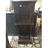 A carved oak cupboard with s single door and exter