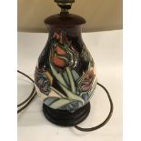 A moorcroft lamp decorated with flowers and foilag