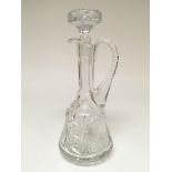 A tall cut glass decanter with an accompanying sto