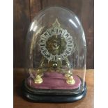 A brass skeleton clock under a glass dome.
