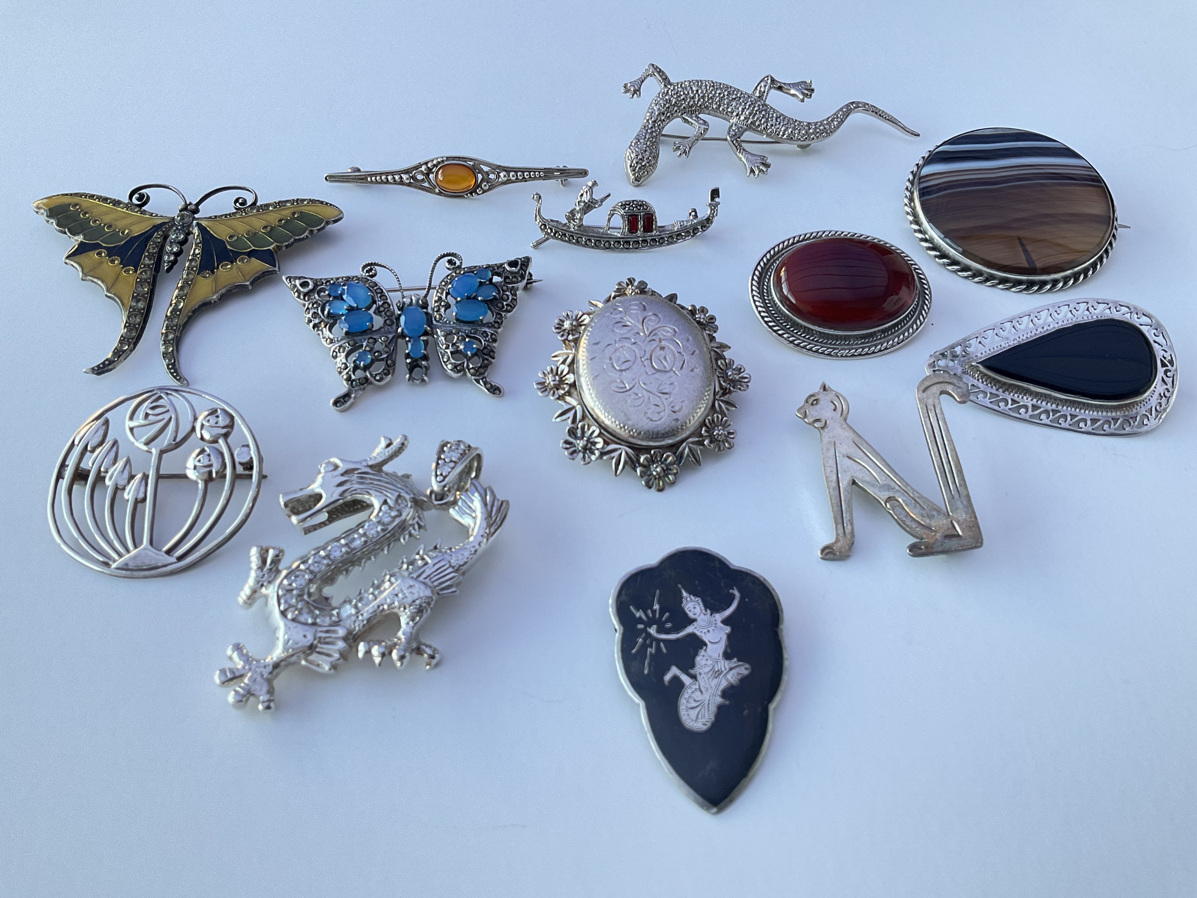 A collection of silver brooches, dragon & butterfl