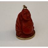 A Chinese 18ct gold and carved coral Buddha charm.