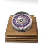 A millefiori paperweight stopper on a wooden stand