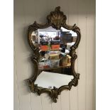 A gilt framed wall mirror with a shell and scroll