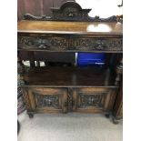 A oak carved buffet the raised back above two draw