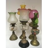 A collection of five brass oil lamps with coloured