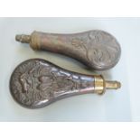 Two copper and brass powder flasks, both with embossed decoration, largest 20cm long.