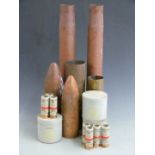 Four large brass shell cases with two nose cones and three tins of Anti-Riot CS baton rounds, all