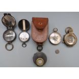 Seven military style compasses including one with a leather case marked SHD and a NEAG Berlin SO