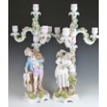 A pair of 19thC German figural candelabra, one with a monkey on the shoulder of a male figure, the