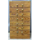 A small oak campaign style collector's chest of seven drawers with brass handles and fittings, W39 x