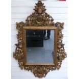 A late 17th/18thC Spanish baroque giltwood mirror with scrolling surround, putti masks and