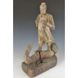 A wooden carved Chinese figure of a robed Chinese man astride a two headed serpent, probably 18thC