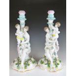 A pair of German porcelain figural candlesticks emblematic of motherhood, with painted and applied