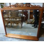 A mahogany overmantel mirror with bevelled glass, integral shelf and removable ornate finial,