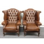 A pair of faux leather wing back Chesterfield armchairs, H107 x W84cm