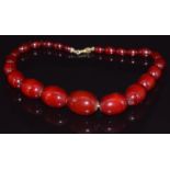 A cherry amber necklace made up of 22 graduated oval beads, 59g, largest bead 3 x 2.1cm