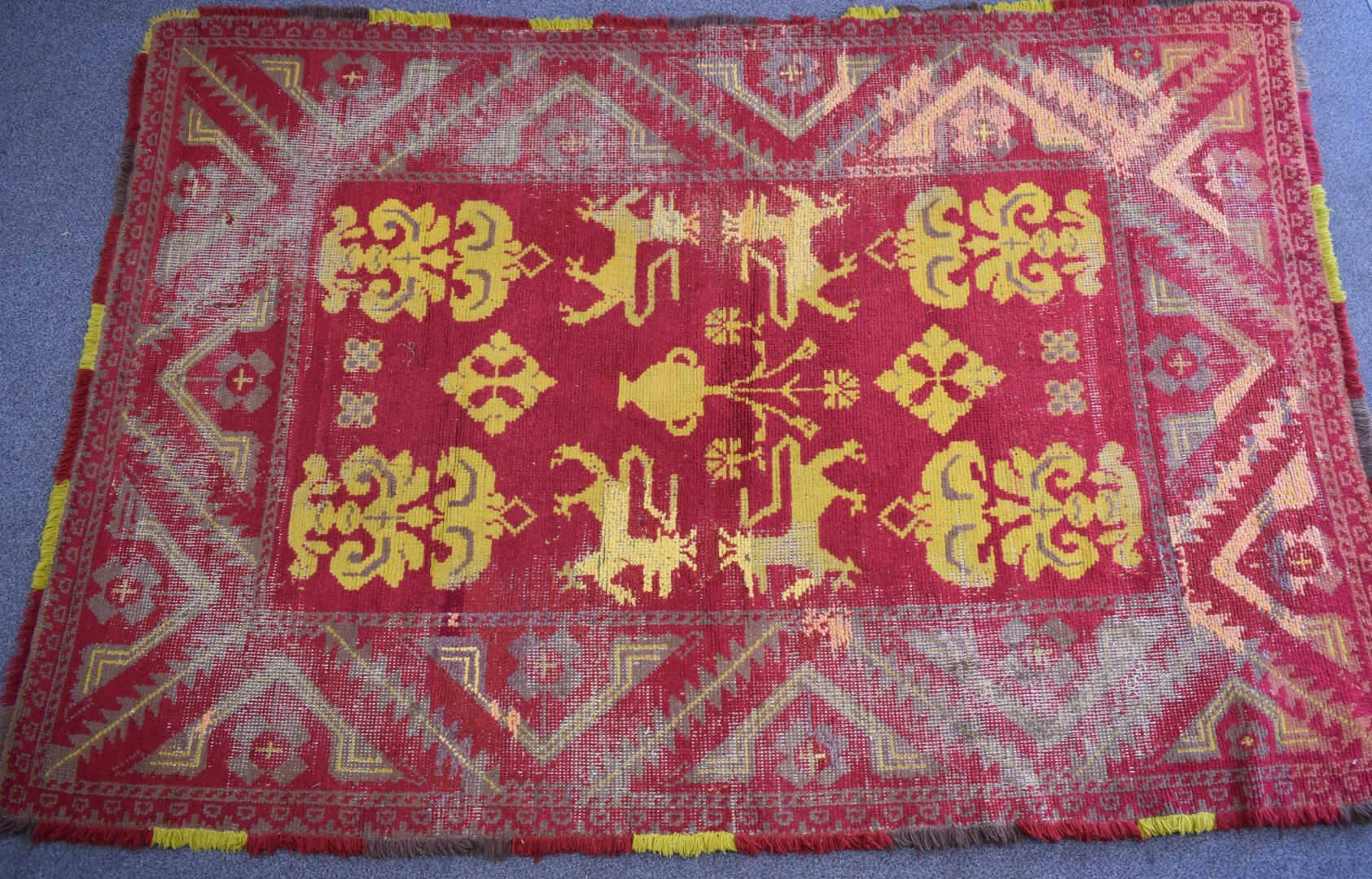 A hand woven wool rug yellow armorial motifs on a wine ground, 305 x 208cm