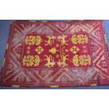 A hand woven wool rug yellow armorial motifs on a wine ground, 305 x 208cm