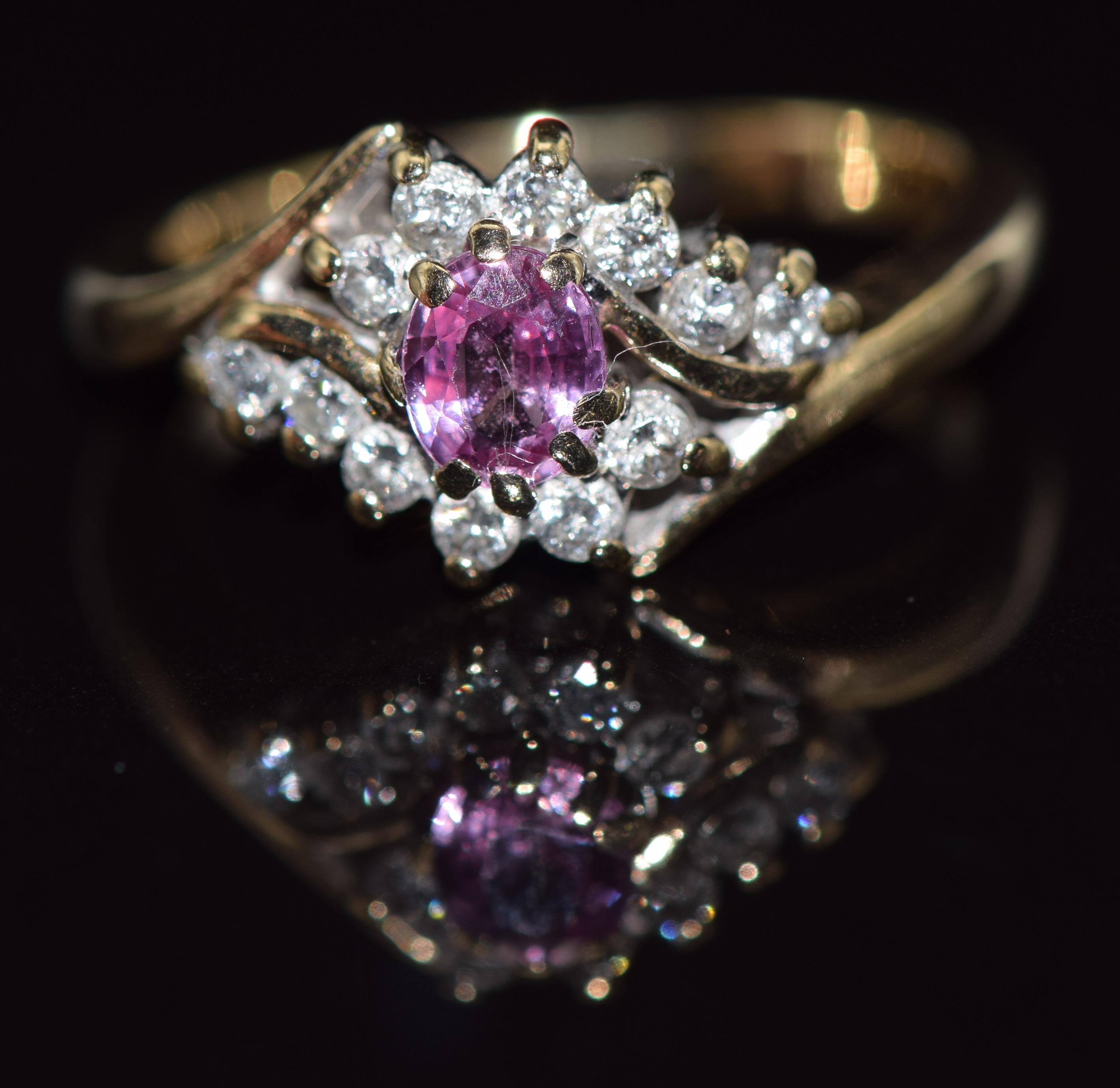 A 9ct gold ring set with an oval cut pink sapphire and diamonds, 3.6g, size K/L