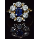 An 18ct gold ring set with an emerald cut sapphire of approximately 0.4ct surrounded by diamonds,