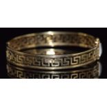 A 9ct gold bangle with pierced Greek key decoration, 15.9g