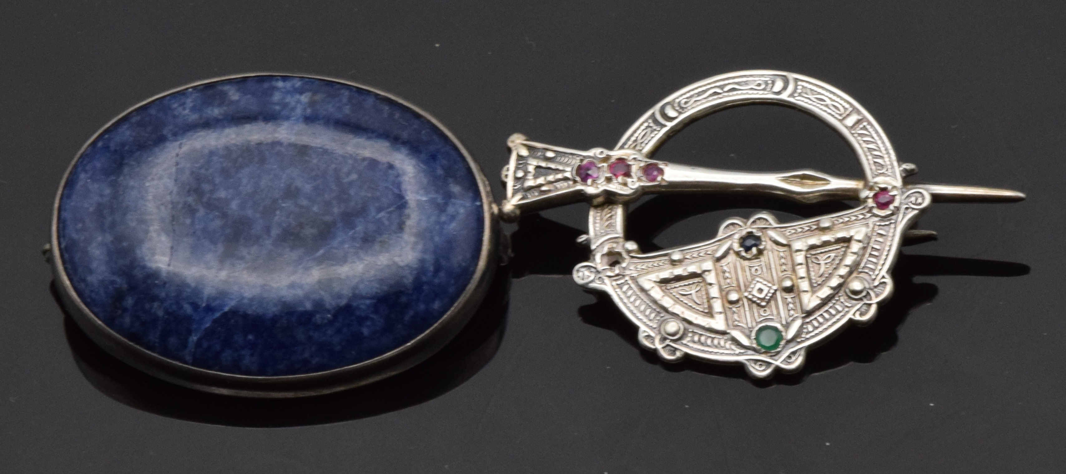 A silver brooch set with a sodalite cabochon and a silver brooch/plaid pin set with rubies, sapphire