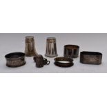 Four various hallmarked silver napkin rings, two white metal shot measures marked 830, Charles