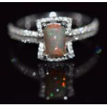 An 18ct white gold ring set with an Australian opal surrounded by diamonds and with further diamonds