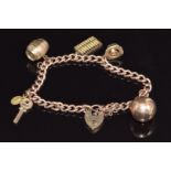 A 9ct gold charm bracelet with five charms including 9ct gold sphere, hat, barrel, abacus, key &
