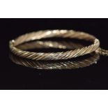 A 9ct gold bangle with twisted ridged design 8.9g