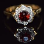 An 18ct gold ring set with a round cut garnet and diamonds, 4g, size N