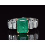 An 18ct white gold ring set with an emerald cut emerald and four baguette cut diamonds, total