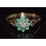 A 9ct gold ring set with a diamond surrounded by emeralds, 1.3g, size M