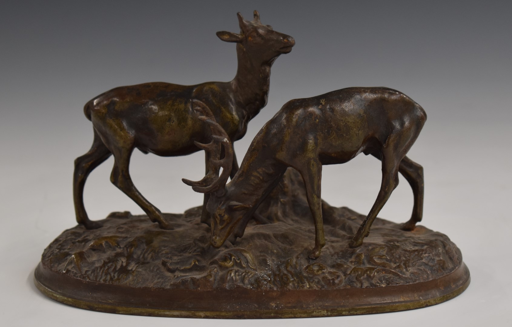 Cast metal model of a pair of deer on naturalistic oval base, L20cm