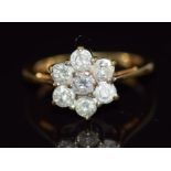 An 18ct gold ring set with seven round cut diamonds in a flower cluster, total diamond weight