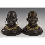 Pair of bronze and gilt metal African head inkwells with hinged lids, on circular bases, bearing