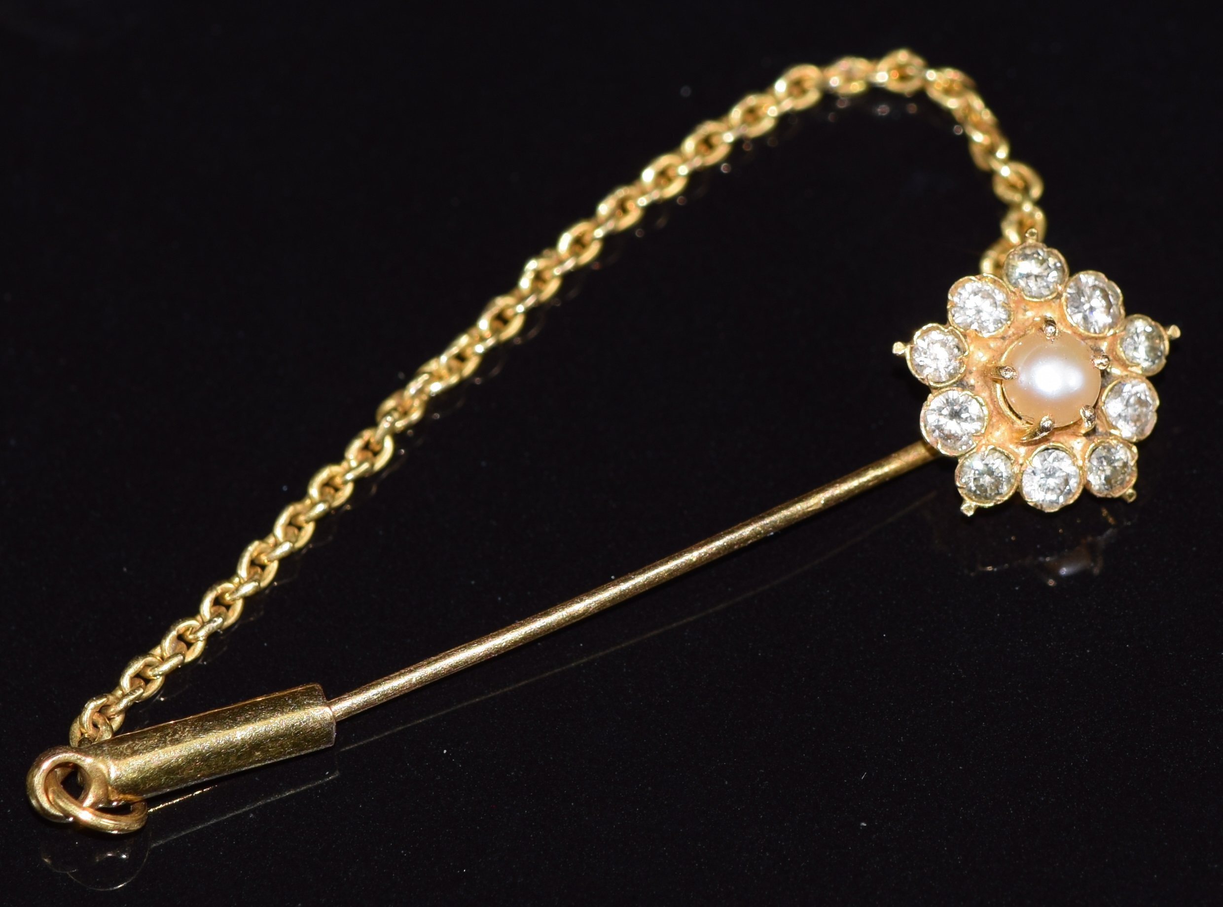 An 18ct gold stick pin set with a pearl surrounded by diamonds, 2.1g, 3.6cm long