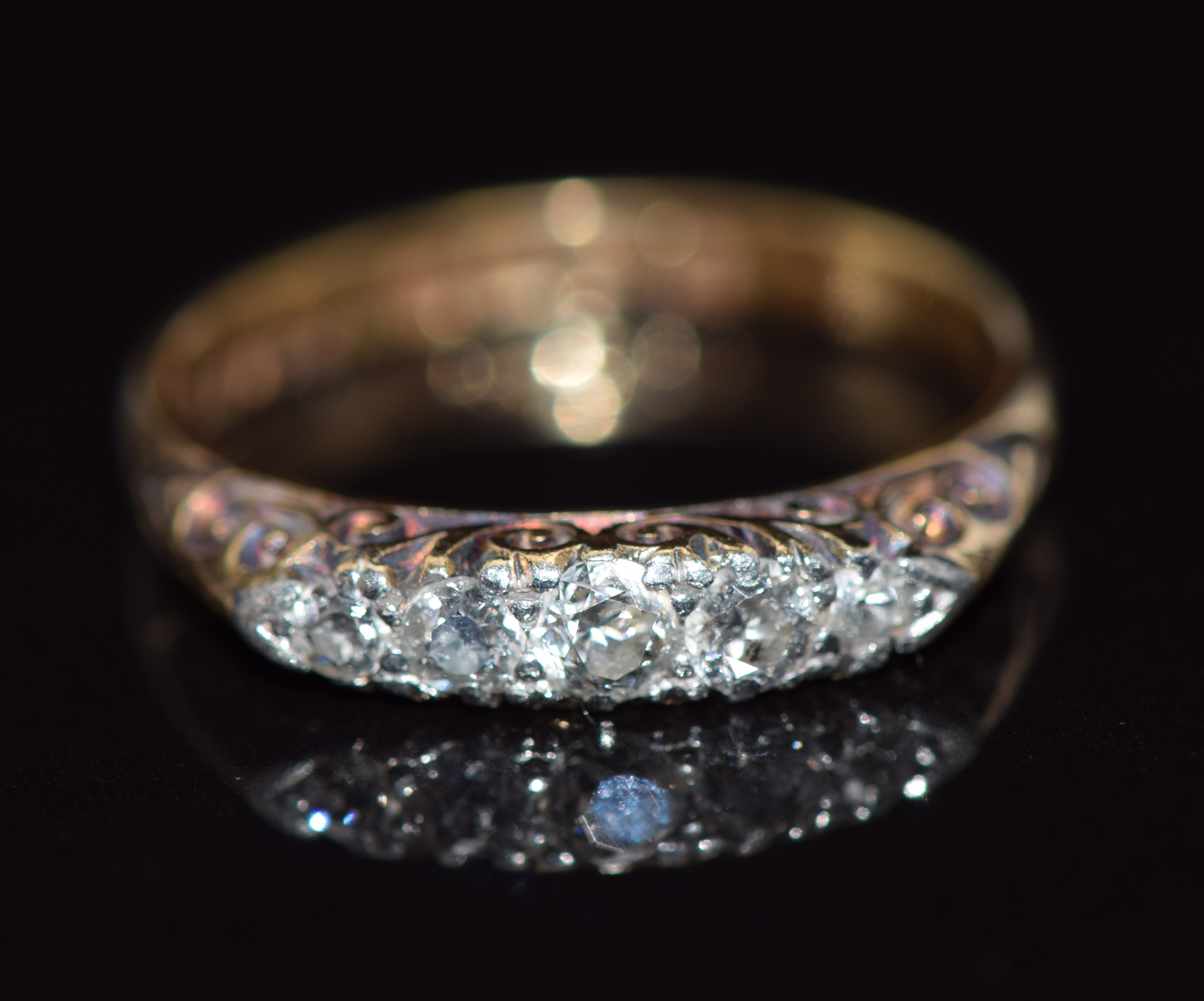 An 18ct gold ring set with five diamonds in a scrolling setting, 2.8g, size N