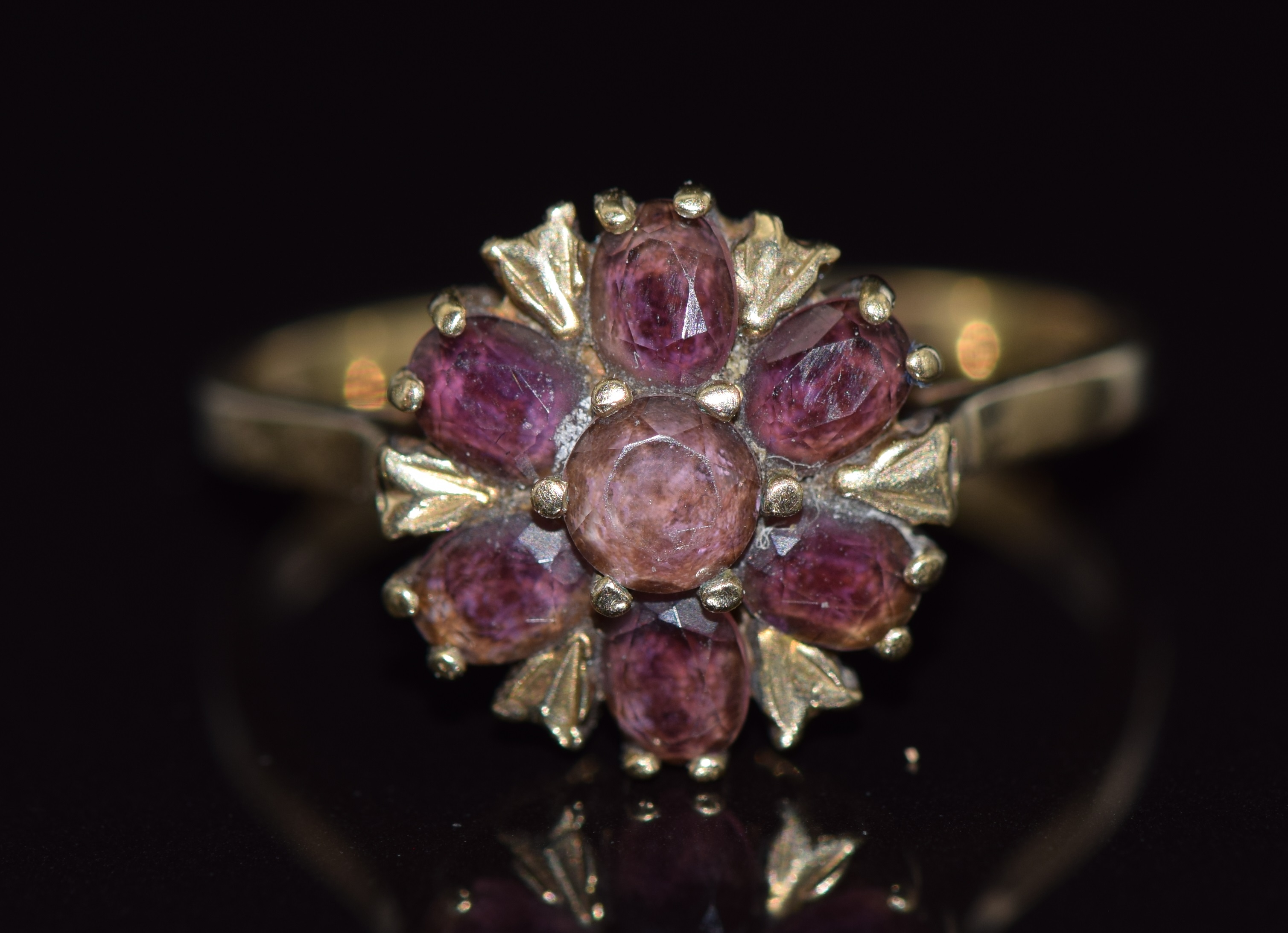 A 9ct gold ring set with a round and oval cut garnets in a cluster, 2.7g, size O