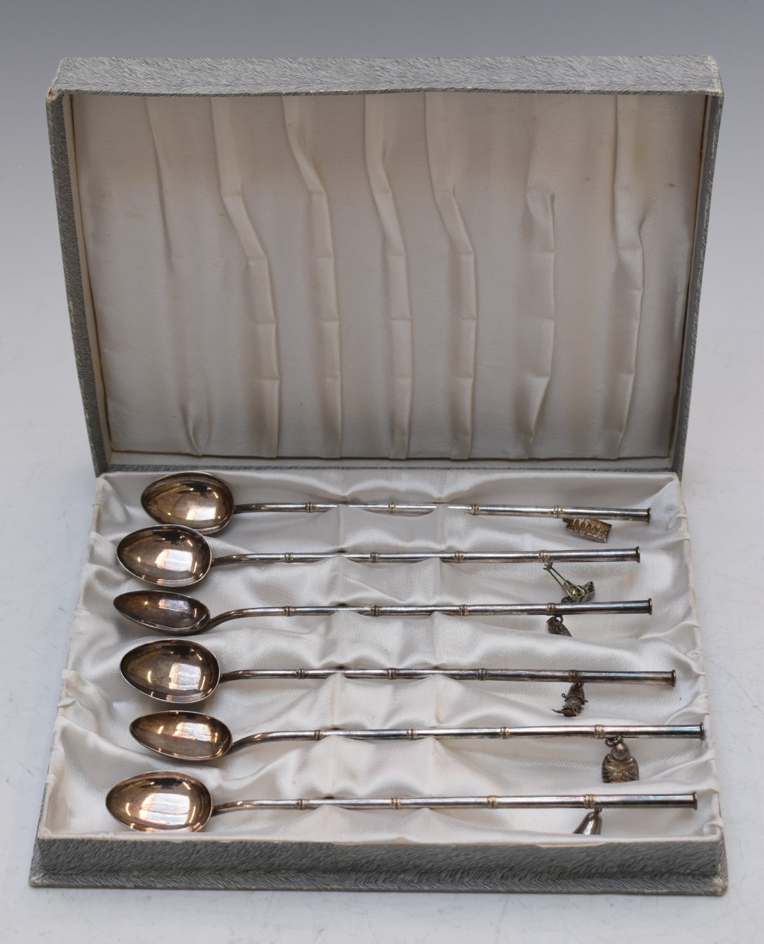 Set of six white metal sundae or ice cream spoons with Eastern charms hanging from the handles, each