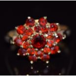 A 9ct gold ring set with round cut garnets in a cluster, 3.5g, size O