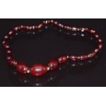 A cherry amber necklace made up of 27 oval beads, largest bead 2.5 x 1.7cm, 29.6g