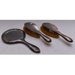 George V hallmarked silver three piece dressing table set comprising hand mirror and two brushes,