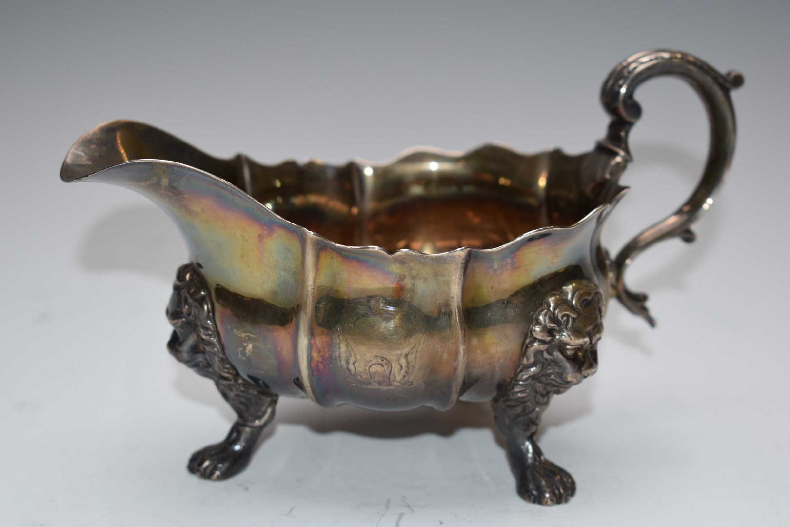 19thC hallmarked silver sauce boat with scrolling handle, raised on lion paw and mask feet, marks