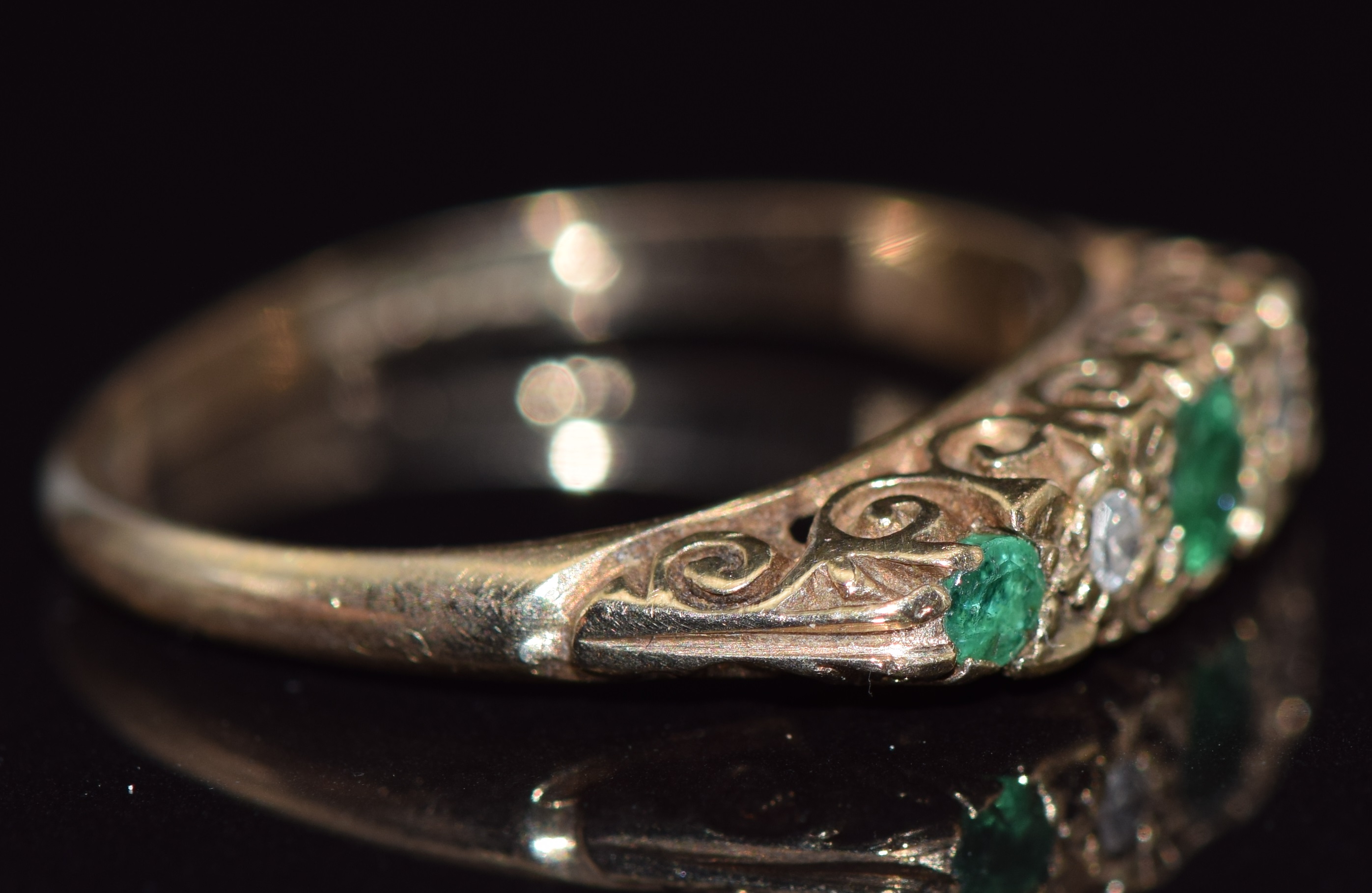 A 9ct gold ring set with round cut emeralds and diamonds in a scrolling setting, 2.4g, size M - Image 2 of 2