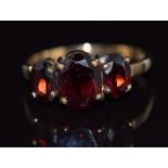 A 9ct gold ring set with three oval cut garnets, 2g, size K