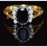 An 18ct gold ring set with an oval cut sapphire and eight diamonds, 3.6g, size O