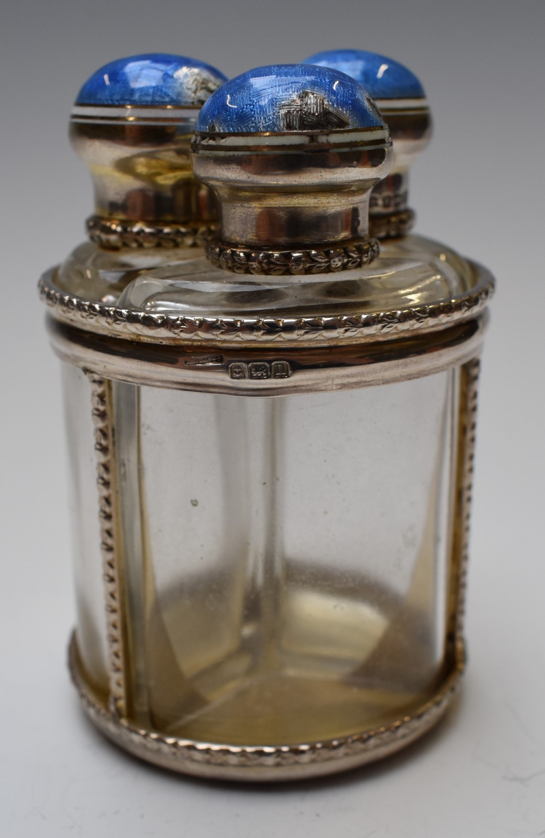 George V hallmarked silver and guilloché enamel three bottle scent bottle set, Birmingham 1912,