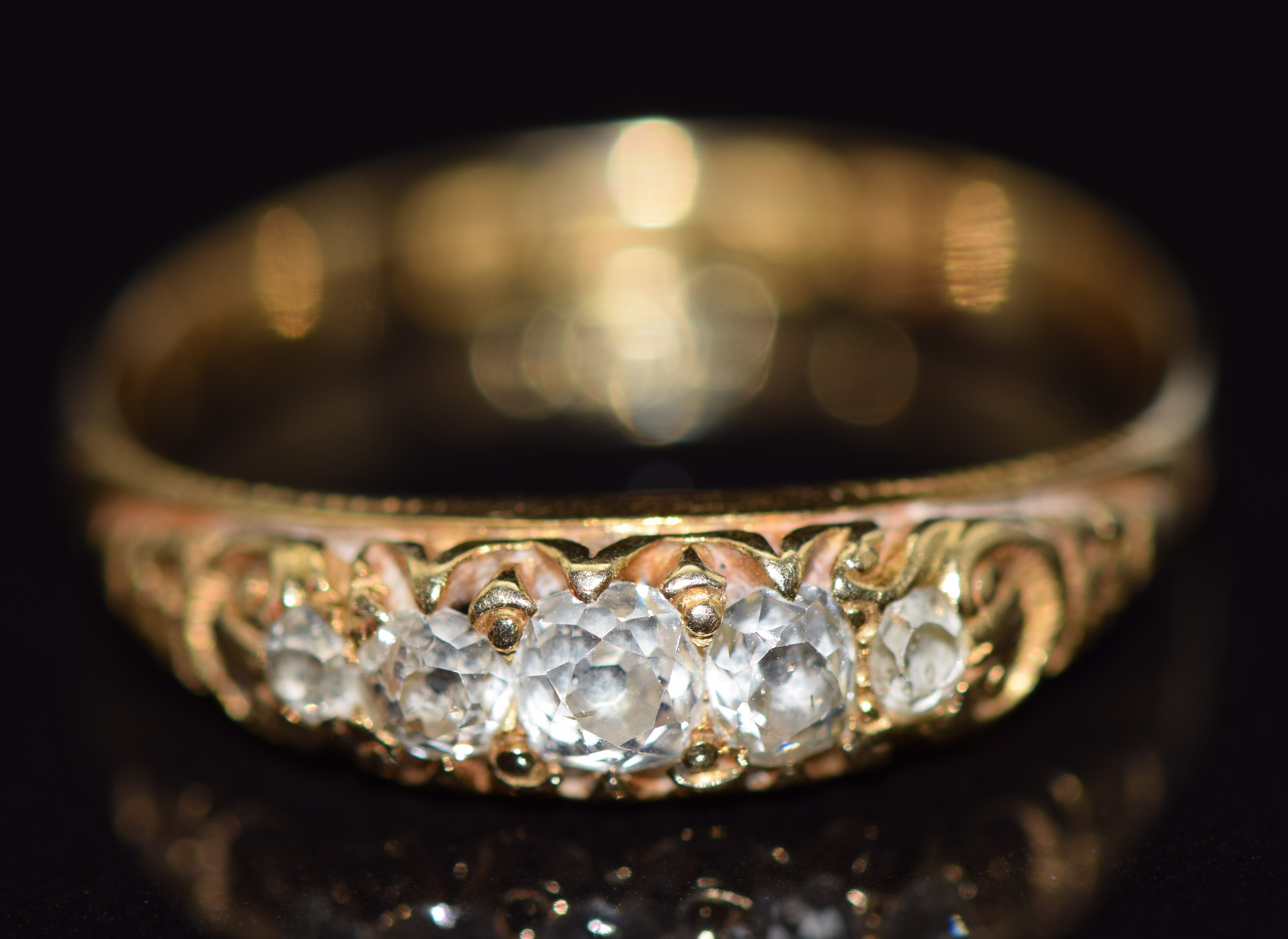 An 18ct gold ring set with five old cut diamonds in a scrolling setting, Birmingham 1922, 2.6g, size